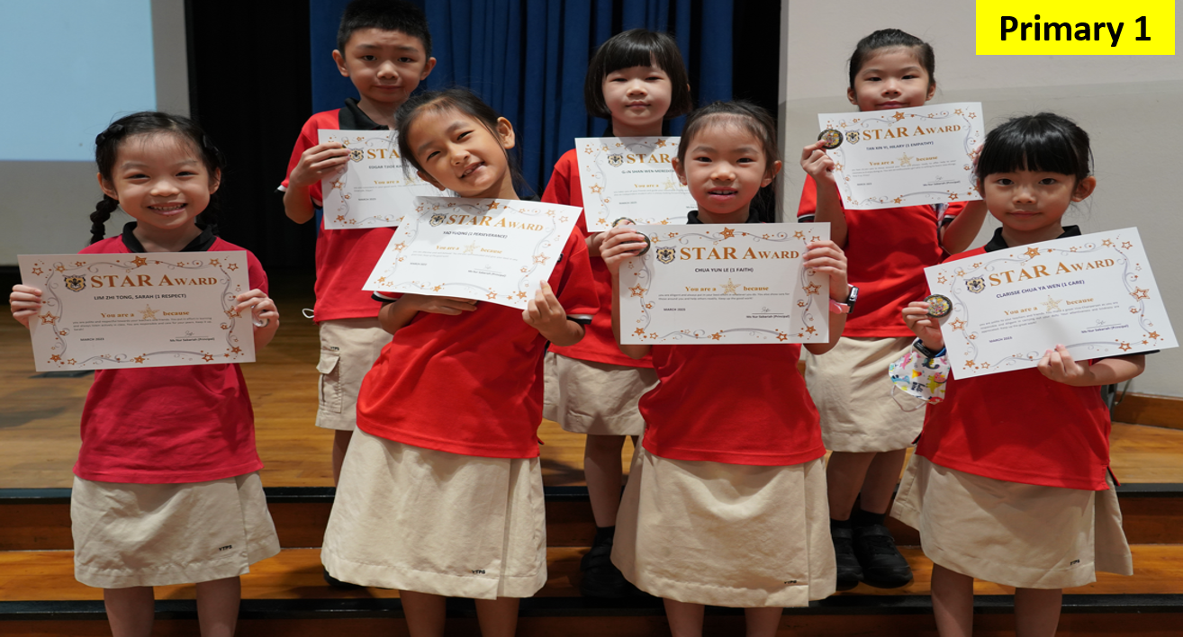 Seven Primary 1 students in red uniforms proudly hold Star Award certificates while posing together on stage.